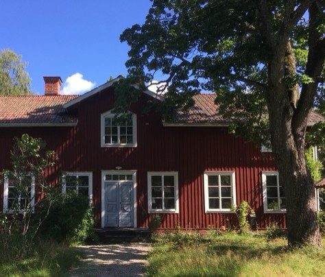 Ranbogården i Mo, Hälsingland — rödmålat trähus omgivet av träd och grönska