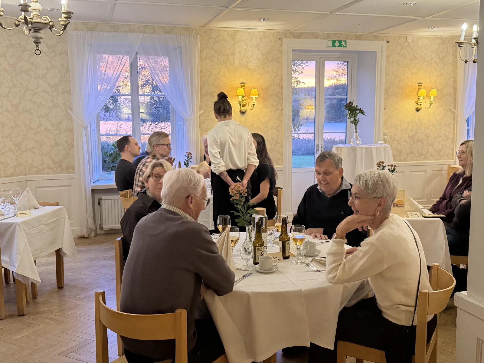 Gäster vid dukade bord under historisk middag på Hjälmared Herrgård